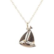 A yellow metal pendant in the form of a boat on chain, the chain marked 9k,