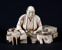 A late 19th century Japanese carved ivory okimono, depiciting a cross-legged cobbler and his wares,