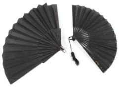 Two 20th century folding fans, one with with a black and red fabric leaf painted with flowers,