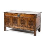 An 18th century oak paneled coffer with plank top with wire hinges above four carved panels