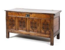 An 18th century oak paneled coffer with plank top with wire hinges above four carved panels