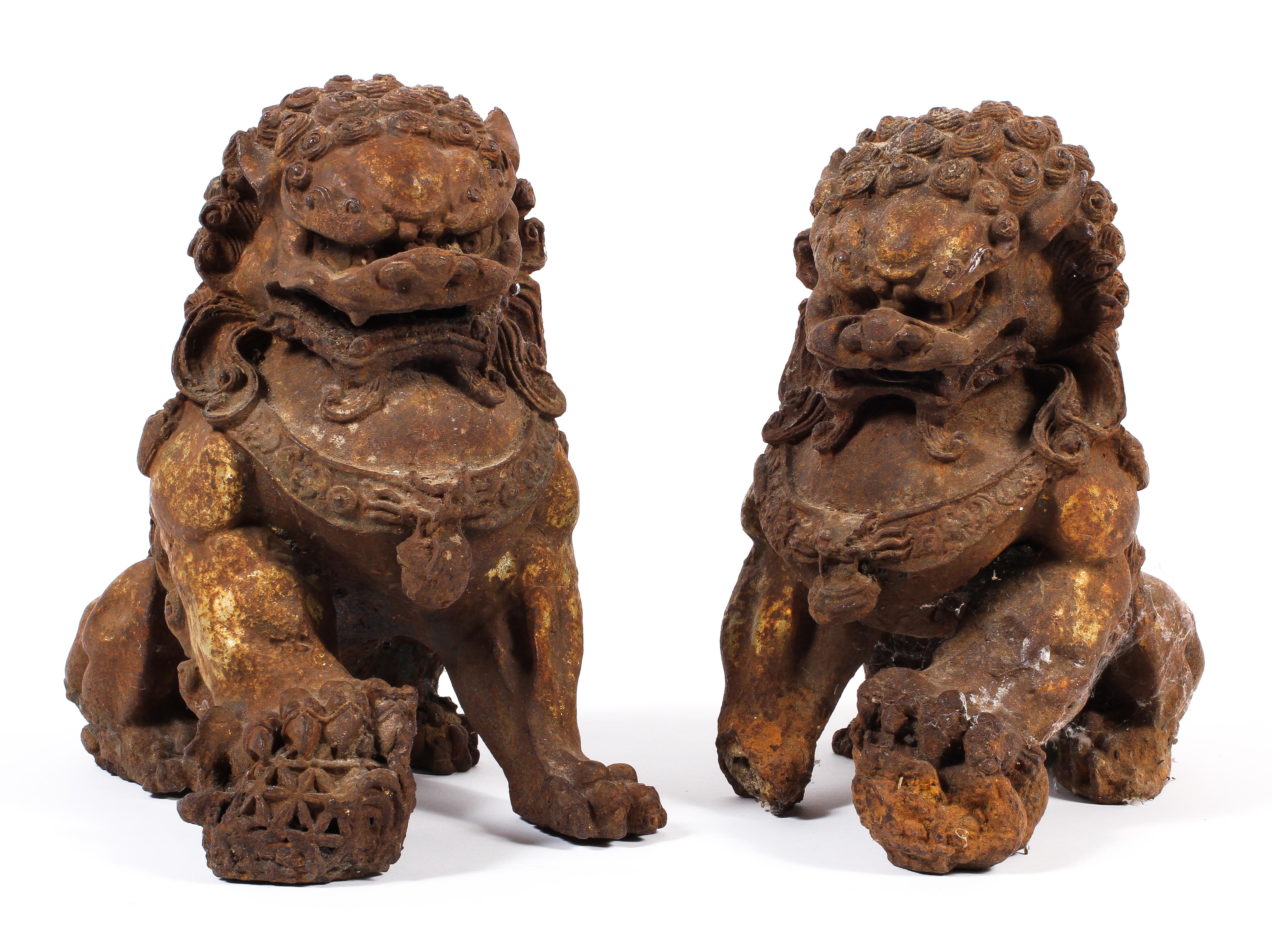 A pair of Chinese cast iron lions, each modelled seated with front paw on a brocaded ball,