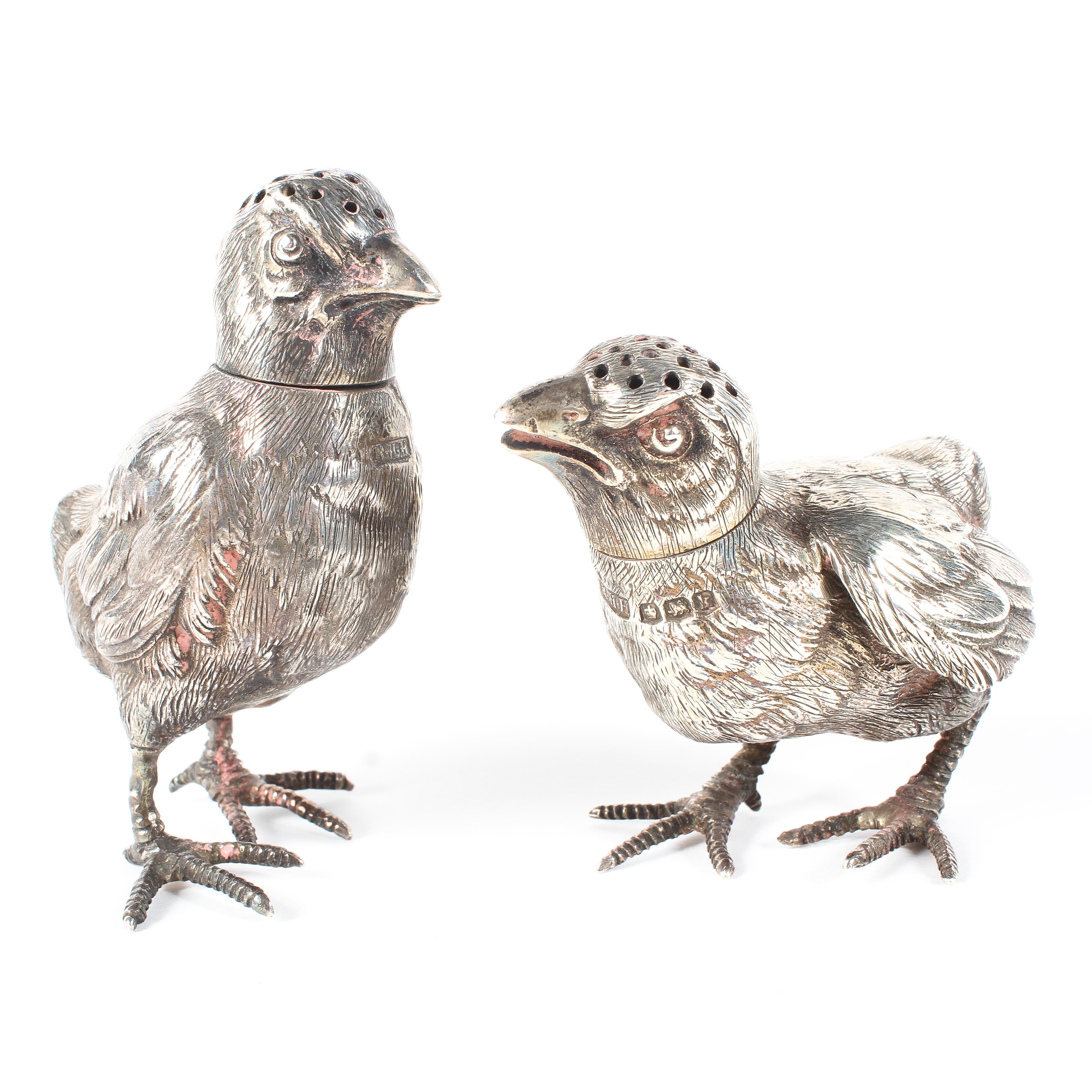 A pair of silver cruets in the form of chicks with removable heads,