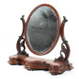 A Victorian mahogany oval swing mirror flanked by acanthus supports above three lidded compartments