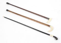 Three Victorian carved ivory mounted walking sticks or canes, one with a wrythen turned handle,