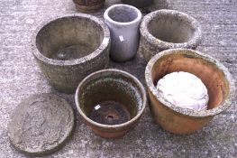 An assortment of stone planters, a stone plaque and a garden ornament.