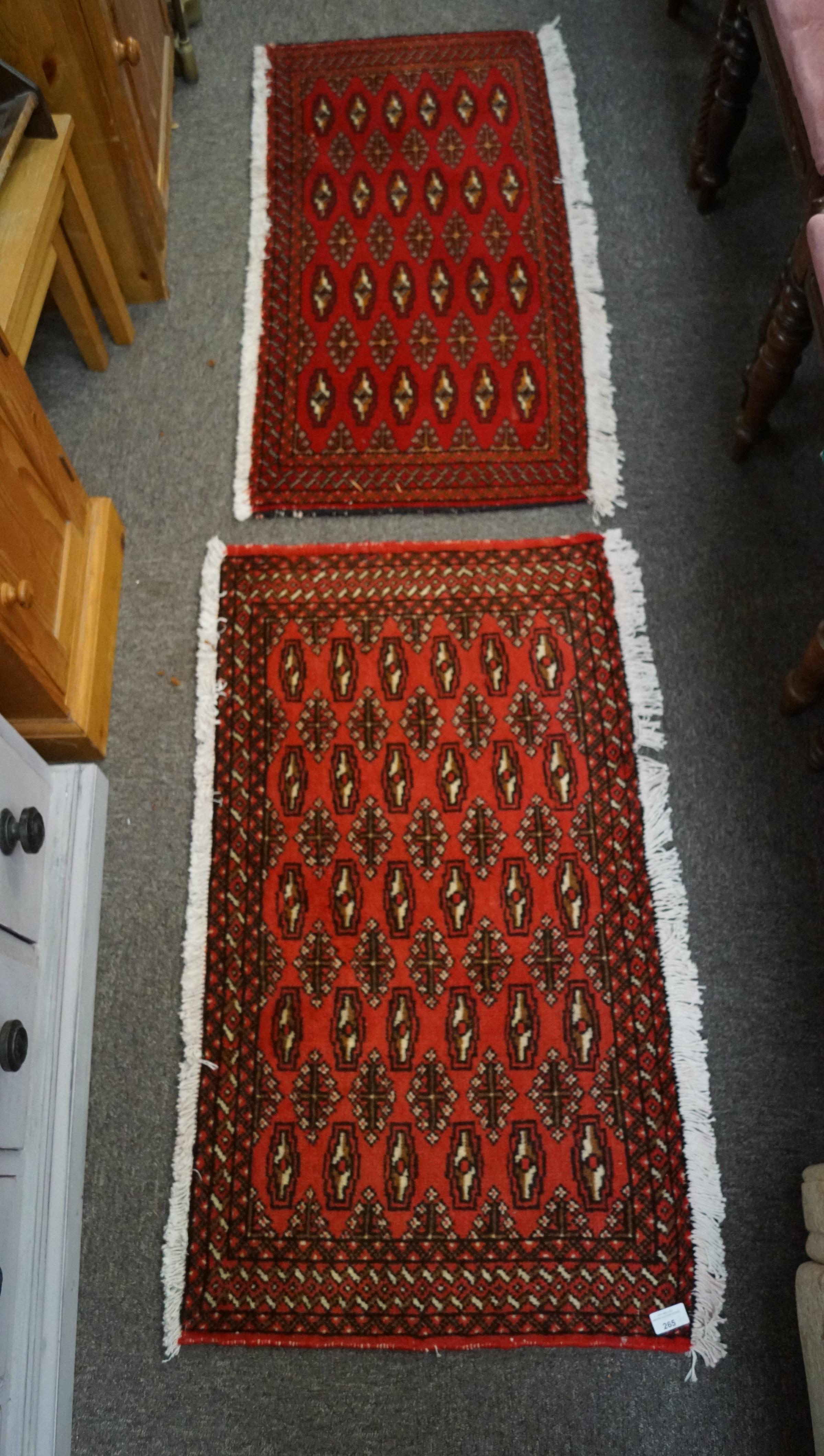 Two small Turkaman rugs with beige and black patterns on a red ground.
