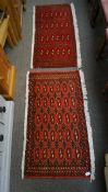 Two small Turkaman rugs with beige and black patterns on a red ground.