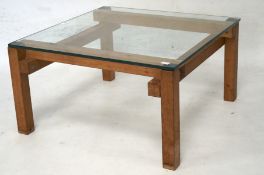 A contemporary wood and glass topped coffee table on square supports.