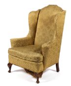A Queen Anne style wing back upholstered armchair.