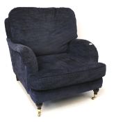 A large blue upholstered armchair on turned supports and casters.