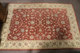 A rust ground rug with cream floral border.
