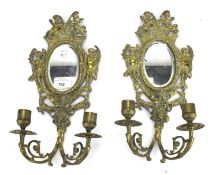 A pair of early 20th century brass two-light wall sconces with mirrored backs.