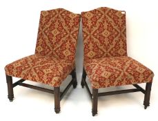 A pair of upholstered mahogany chairs, on carved square supports and casters,