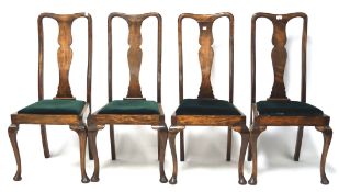 Four stained wooden dining chairs.