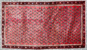 an Arak Rug with red repeated design on a red ground.