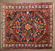 An early 20th century Eastern hand woven carpet with central medallion on a red ground and