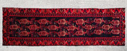 A Hamedan runner with central repeated medallions on a red and blue ground 400x100cm
