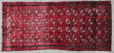 A Torkaman rug with repetative medallions on a red ground within a border.