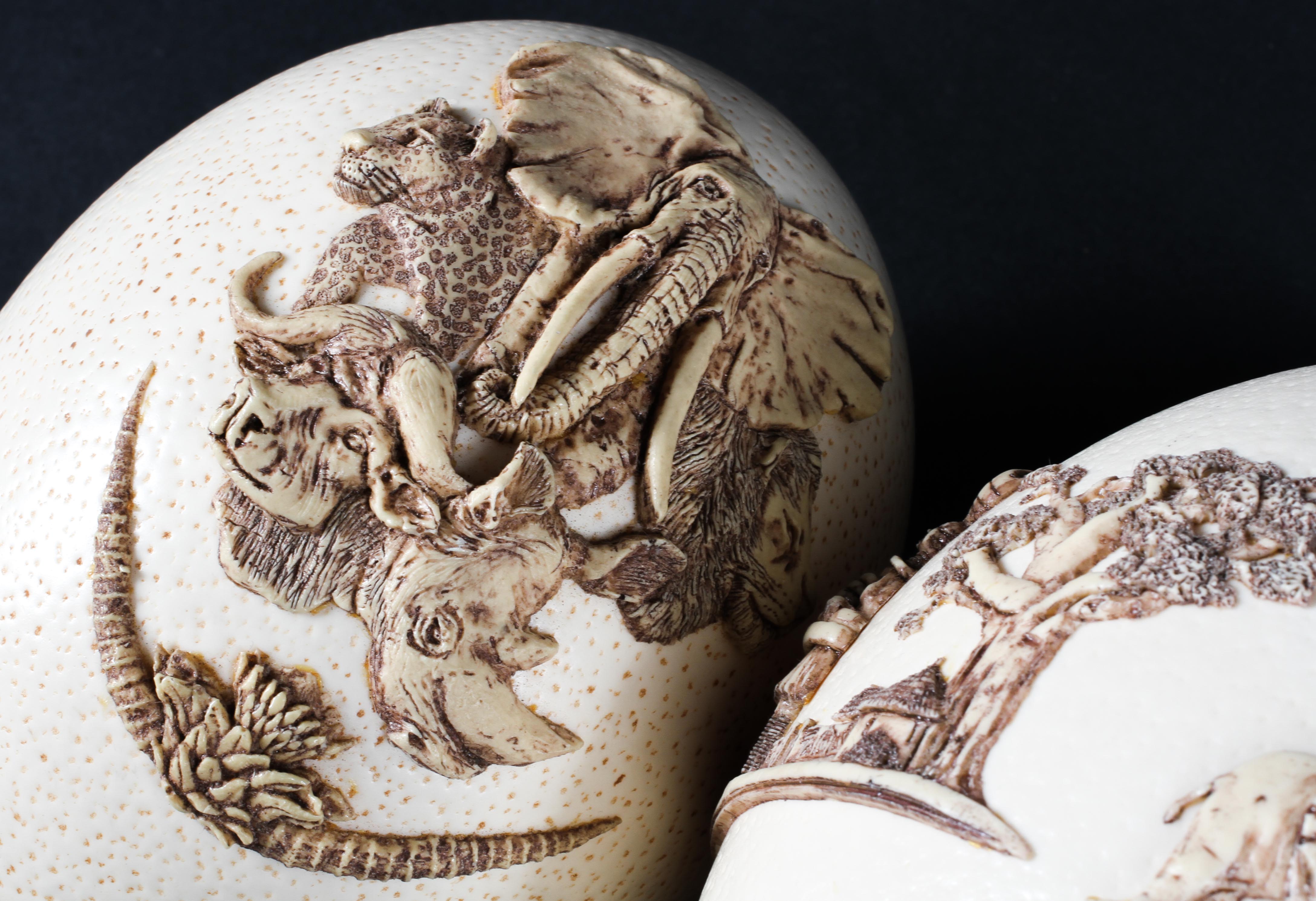 Two ostrich eggs decorated with applied African figures and a collage of African animals in relief. - Image 2 of 2