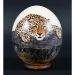 A hand painted ostrich egg, painted with a Leopard. Signed GINA mounted on a stand,approx.