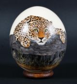 A hand painted ostrich egg, painted with a Leopard. Signed GINA mounted on a stand,approx.