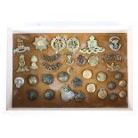 A collection of military cap badges and buttons. Including Royal Scots, RAF, etc, mounted in frame.