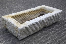 A rectangular stone garden trough with wavy textured surface.