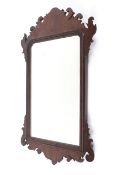 A Georgian mahogany framed mirror, with scrolling foliate cresting and mantling,