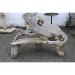 A curved wooden garden bench of naturalistic form on three solid legs.