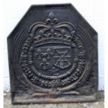 A cast iron fire back decorated in relief with a coat of arms surrounded by ribbons.