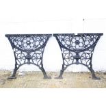A pair of painted cast iron table ends pierced with flowers and an urn.