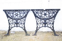 A pair of painted cast iron table ends pierced with flowers and an urn.