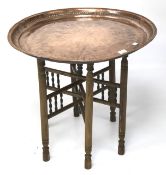 A large circular copper tray on a foldable bamboo stand.