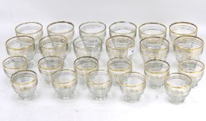 Twenty-three glass beakers with gilt rims.