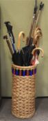 A wicker basket containing walking sticks and umbrellas.