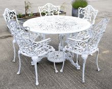 A white painted metal round garden table and five chairs with pierced decoration.