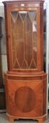 A reproduction veneered corner cabinet.