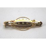 A 9ct gold bar brooch. Set with pearls and garnets and with pierced details. Weight 2.