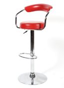 A chrome adjustable bar stool of tubular form upholstered in faux red leather.