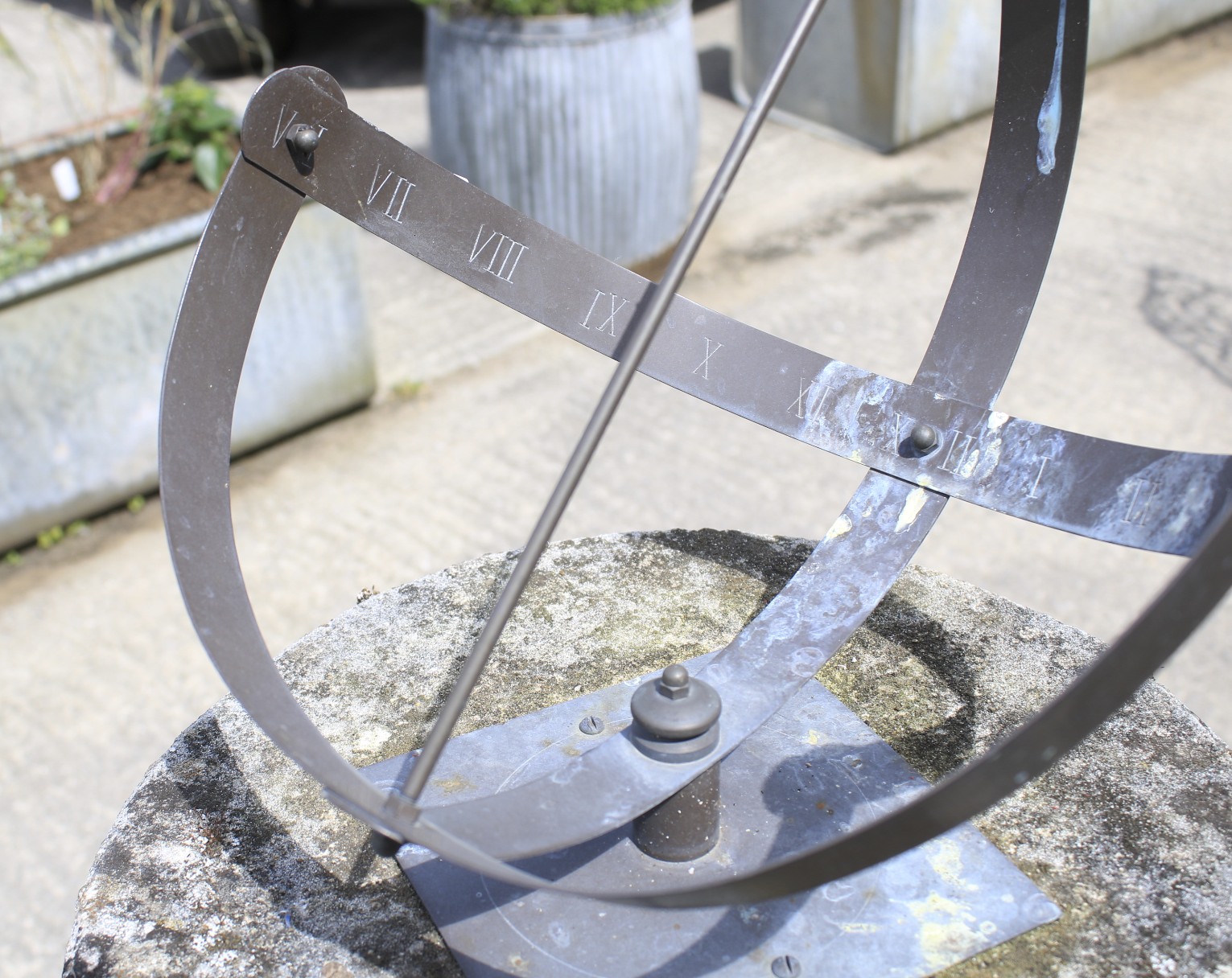 A grey metal sun dial with engraved Roman numerals. Fixed to a composite stone pedestal base. - Image 2 of 2