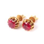 A pair of Middle Eastern yellow metal and ruby single stone stud earrings.