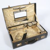 A 1920s green leather carry case fitted with a silver mounted grooming set.