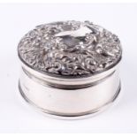 A silver circular embossed ring box.