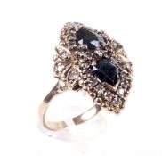 A dark-blue sapphire and diamond dress ring in the form of a stylised shoe buckle.