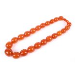 An imitation-amber bead necklace. The 23 oval beads graduated approx 24.5mm x 21.