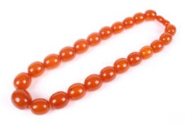 An imitation-amber bead necklace. The 23 oval beads graduated approx 24.5mm x 21.