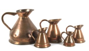 Five 19th century copper measuring jugs.