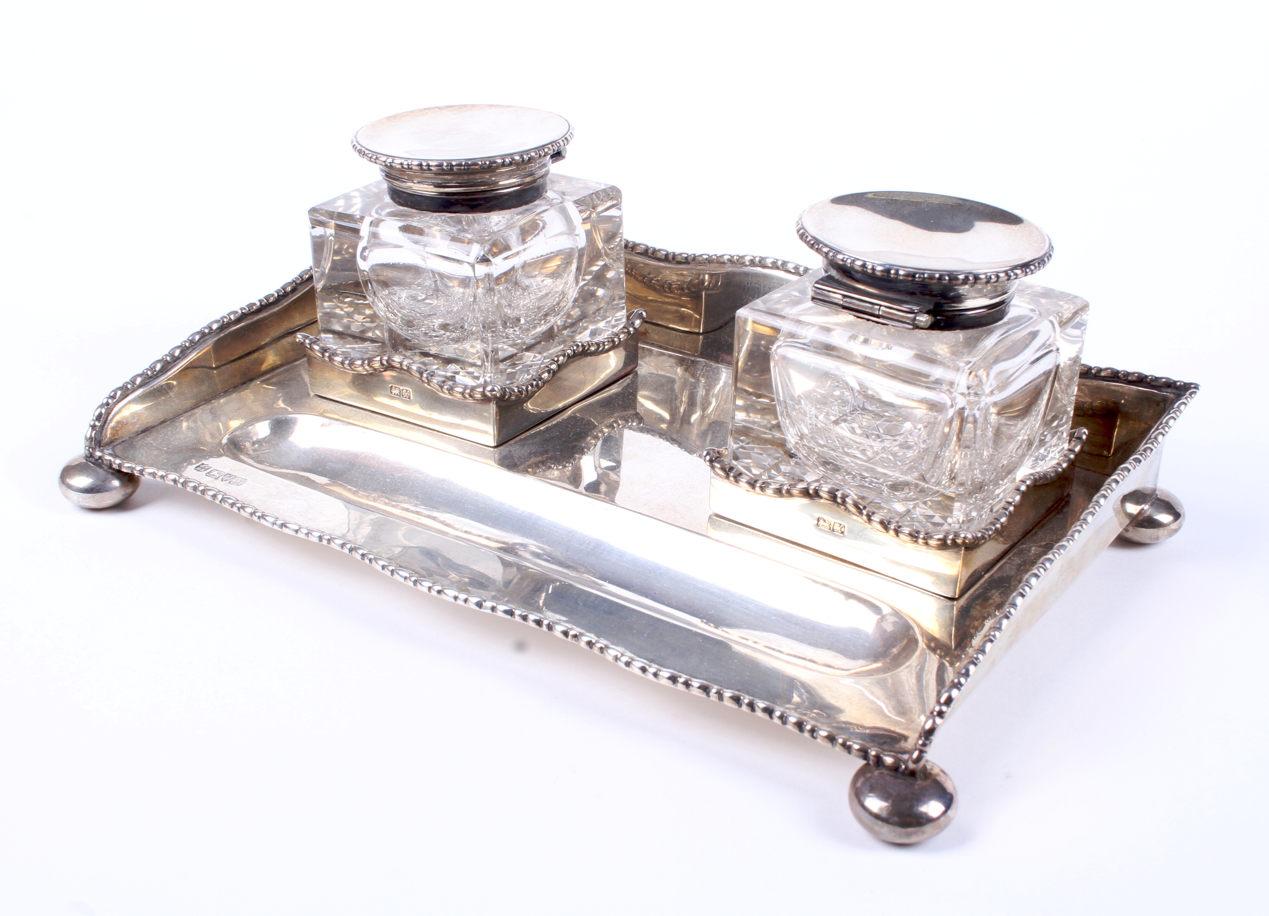 A silver inkstand fitted with two silver-topped glass inkwells.