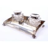 A silver inkstand fitted with two silver-topped glass inkwells.